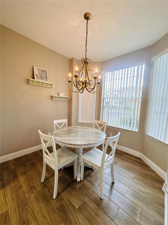A dining area features a round marble-topped table, four white chairs, and a brass chandelier — 1204 S BEACH CIR, KISSIMMEE, FL