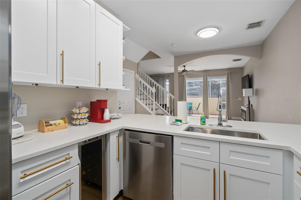 A kitchen features white cabinets, gold hardware, stainless steel appliances, and a quartz countertop — 1204 S BEACH CIR, KISSIMMEE, FL