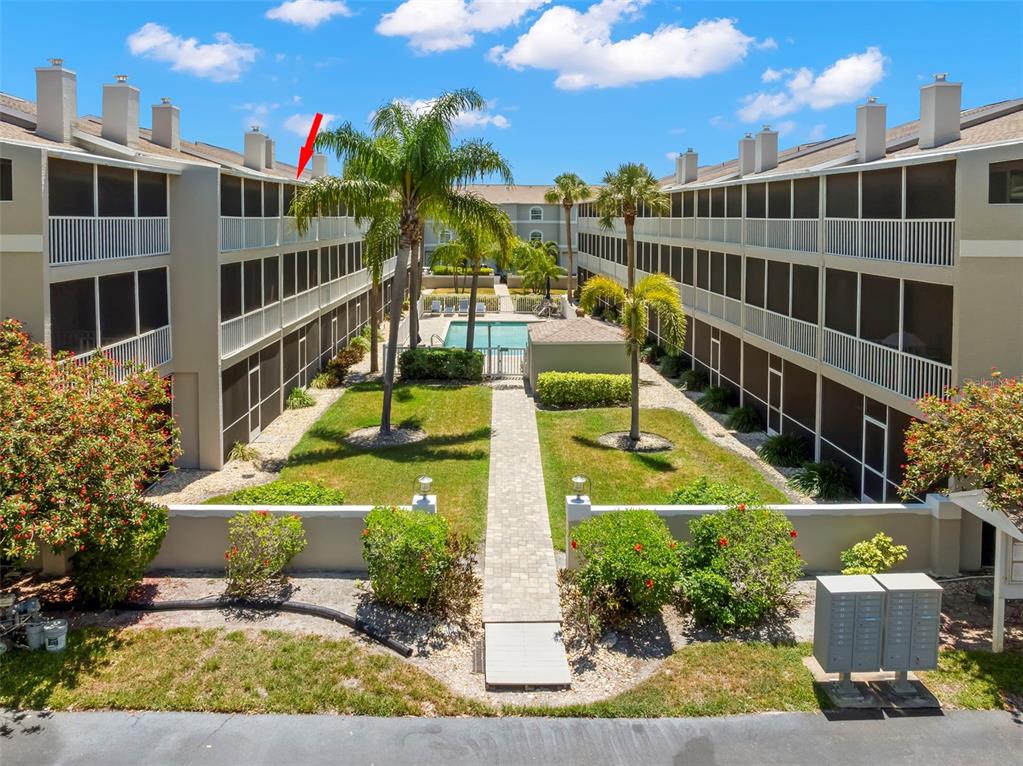 An exterior view of a multi-story apartment complex with a central pool and courtyard — 737 PINELLAS BAYWAY S UNIT 308, ST PETERSBURG, FL