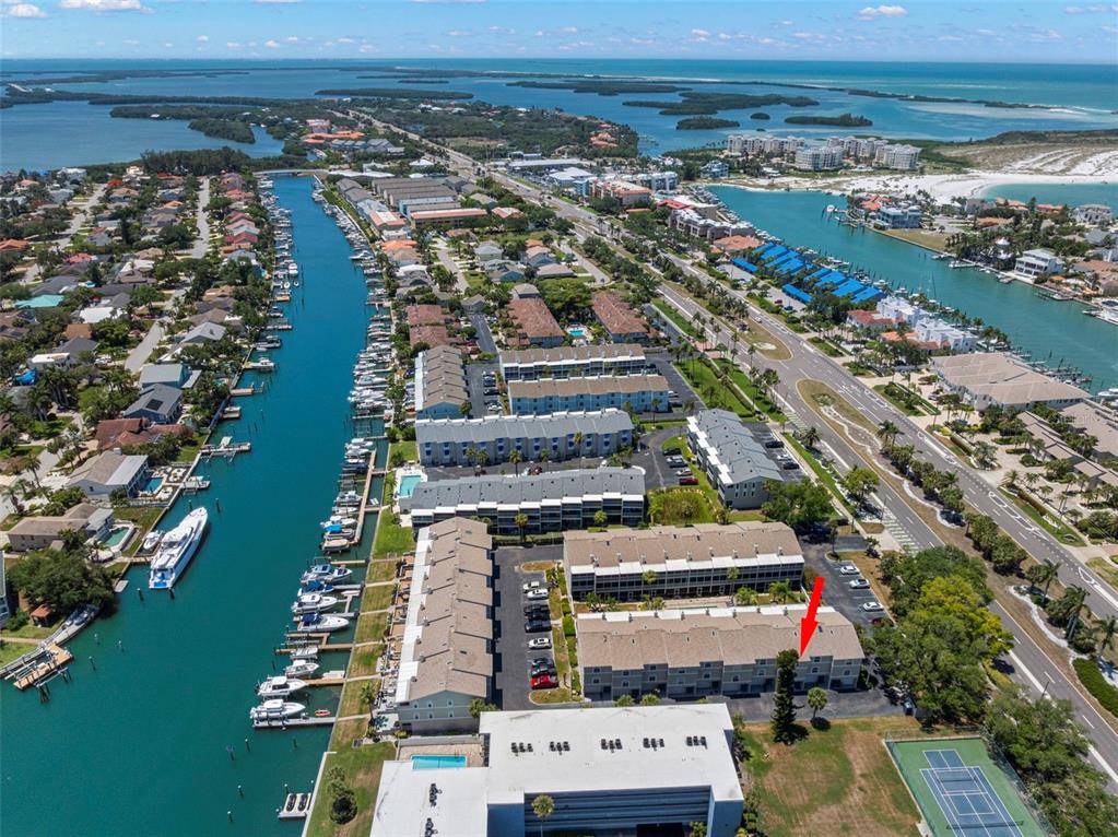 An aerial view shows a multi-story residential complex with boat slips along a canal — 737 PINELLAS BAYWAY S UNIT 308, ST PETERSBURG, FL
