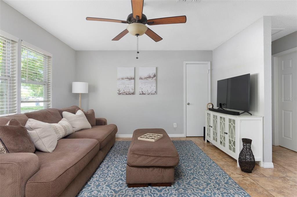 A living room features a brown sofa, a matching ottoman, and a white media console — 1744 26TH AVENUE N, ST PETERSBURG, FL
