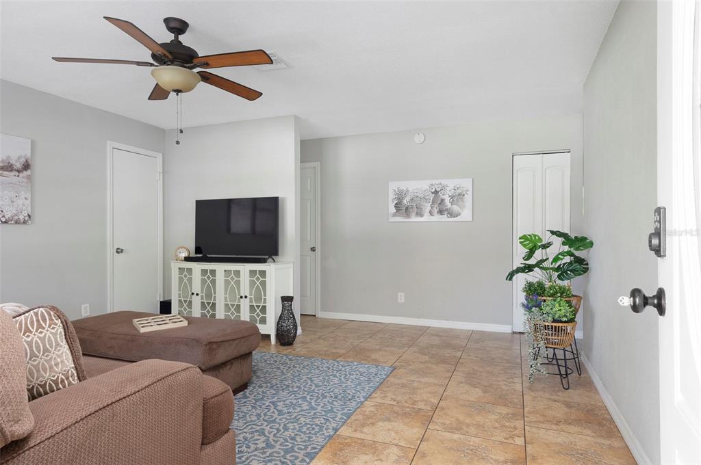 A living room features tile flooring, a ceiling fan, a television console, and a plant — 1744 26TH AVENUE N, ST PETERSBURG, FL