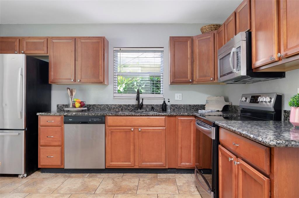 A kitchen with wood cabinets, granite countertops, stainless steel appliances, and tile flooring — 1744 26TH AVENUE N, ST PETERSBURG, FL