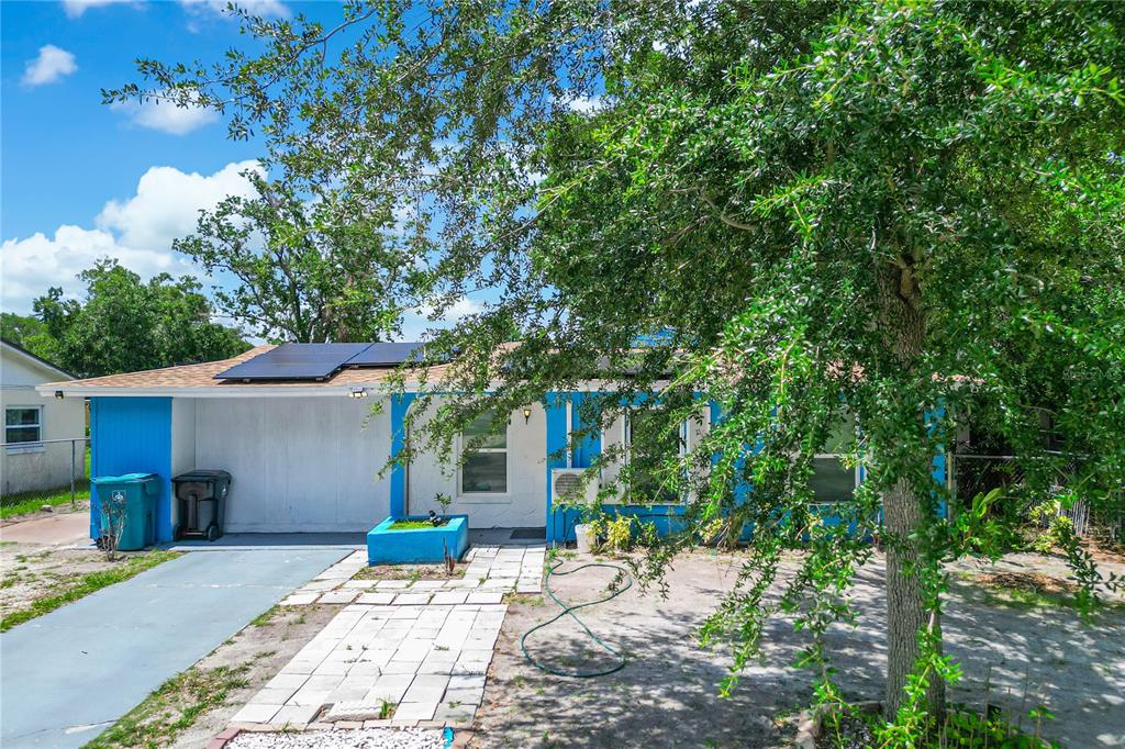 A single-story house with a blue exterior, solar panels, and a large tree in front — 4671 VERGARA COURT, ORLANDO, FL