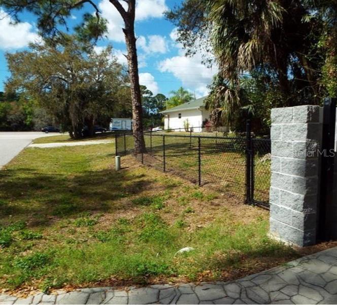 A chain-link fence borders a grassy yard with a white house in the background — 17314 WELLSLEY AVENUE, PORT CHARLOTTE, FL