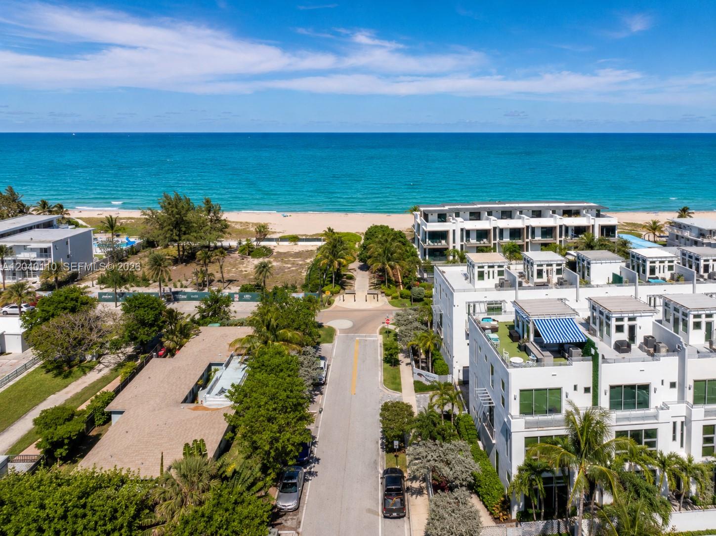 An aerial view shows a coastal street leading to a beach with modern white townhouses — 3406 SE 6th St # 3406, Pompano Beach FL 33062, POMPANO BEACH, FL