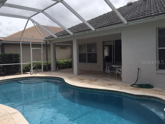 A swimming pool sits on a patio enclosed by a screened lanai behind a house — 17947 COURTSIDE LANDINGS CIRCLE, PUNTA GORDA, FL