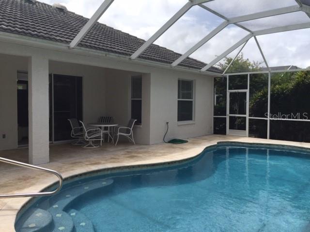 A swimming pool with a screened-in lanai and patio area sits behind a residential home — 17947 COURTSIDE LANDINGS CIRCLE, PUNTA GORDA, FL
