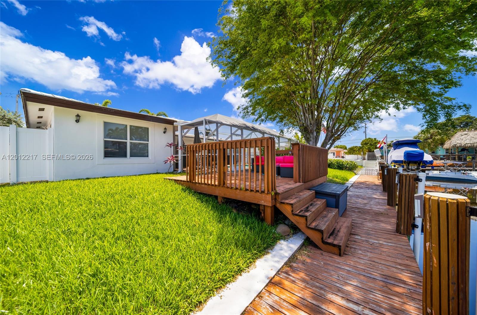 A wooden deck with stairs sits on a grassy lawn beside a boat dock — 31 SE 12th St, Pompano Beach FL 33060, POMPANO BEACH, FL