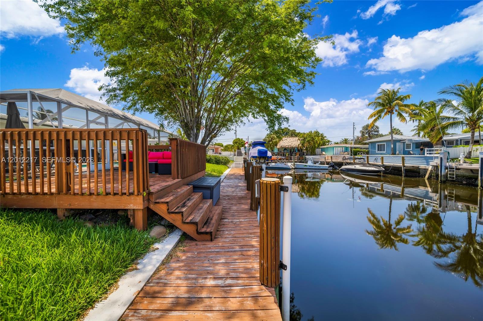 A wooden deck and dock overlook a canal with boats and palm trees — 31 SE 12th St, Pompano Beach FL 33060, POMPANO BEACH, FL