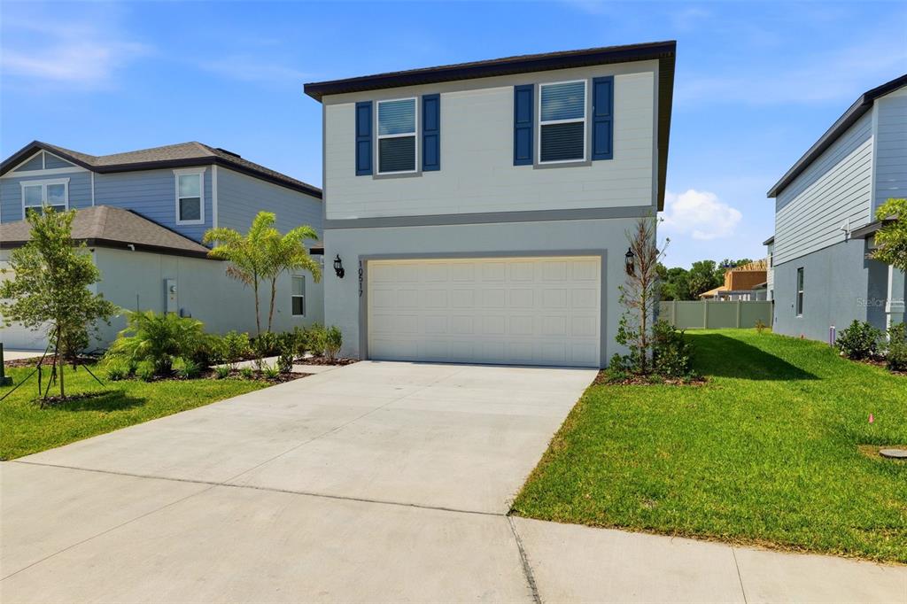 A two-story suburban house with a white garage door, light gray siding, and blue shutters — 10517 HIDDEN BANKS GLEN, PARRISH, FL