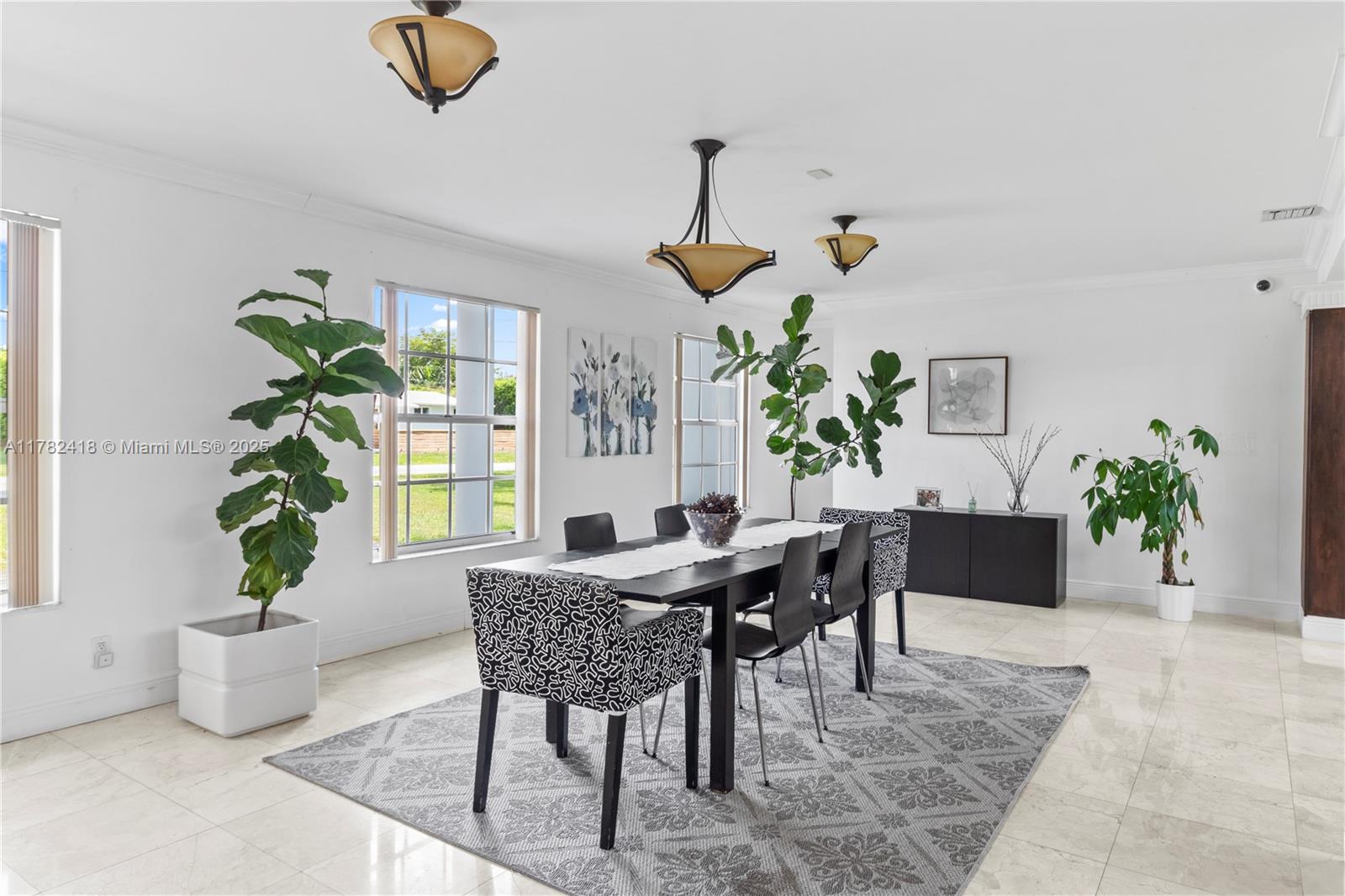 A dining room features a long table, patterned chairs, large potted plants, and tile floors — 8350 SW 98 th St, Miami FL 33156, MIAMI, FL