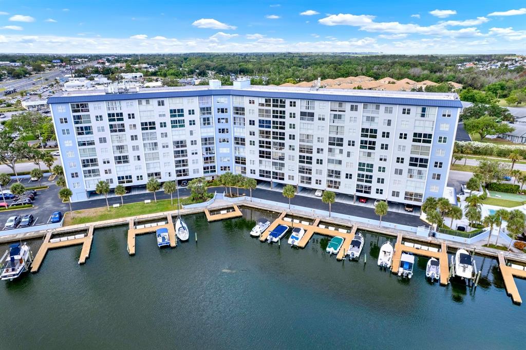 An aerial view shows a large multi-story apartment building situated along a private boat dock — 4939 FLORAMAR TERRACE UNIT 204, NEW PORT RICHEY, FL