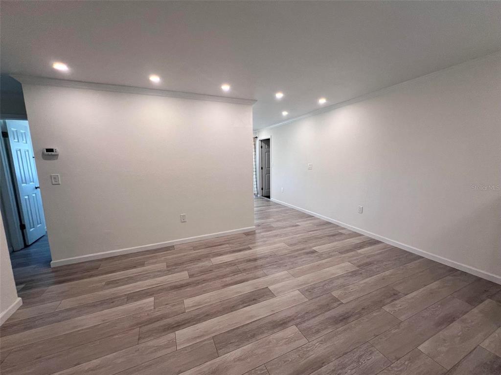 An empty room features light wood-look flooring, white walls, and recessed ceiling lighting — 3339 VAN NUYS LOOP, NEW PORT RICHEY, FL