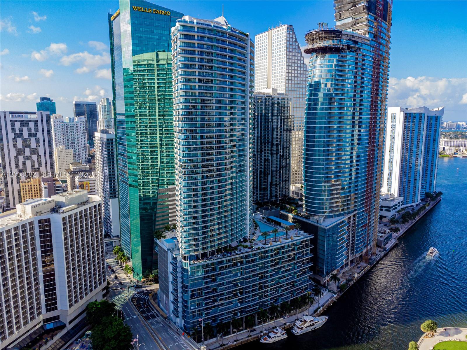 An aerial view shows several modern glass skyscrapers in a city along a river — 200 Biscayne Boulevard Way # 5001, Miami FL 33131, MIAMI, FL
