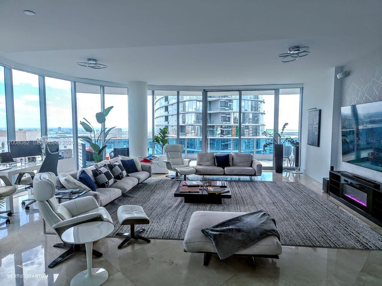A modern living room features floor-to-ceiling windows, a large area rug, and city views — 200 Biscayne Boulevard Way # 5001, Miami FL 33131, MIAMI, FL