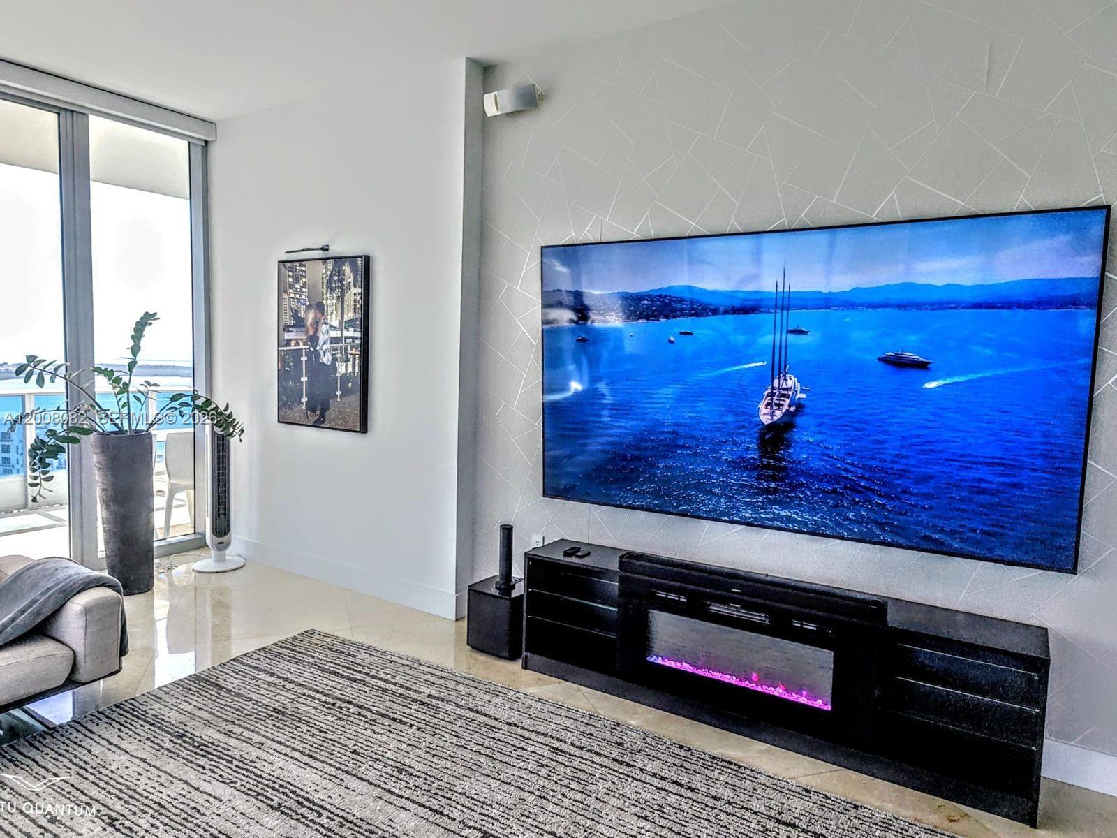 A living room features a large wall-mounted television above a black media console with a fireplace — 200 Biscayne Boulevard Way # 5001, Miami FL 33131, MIAMI, FL