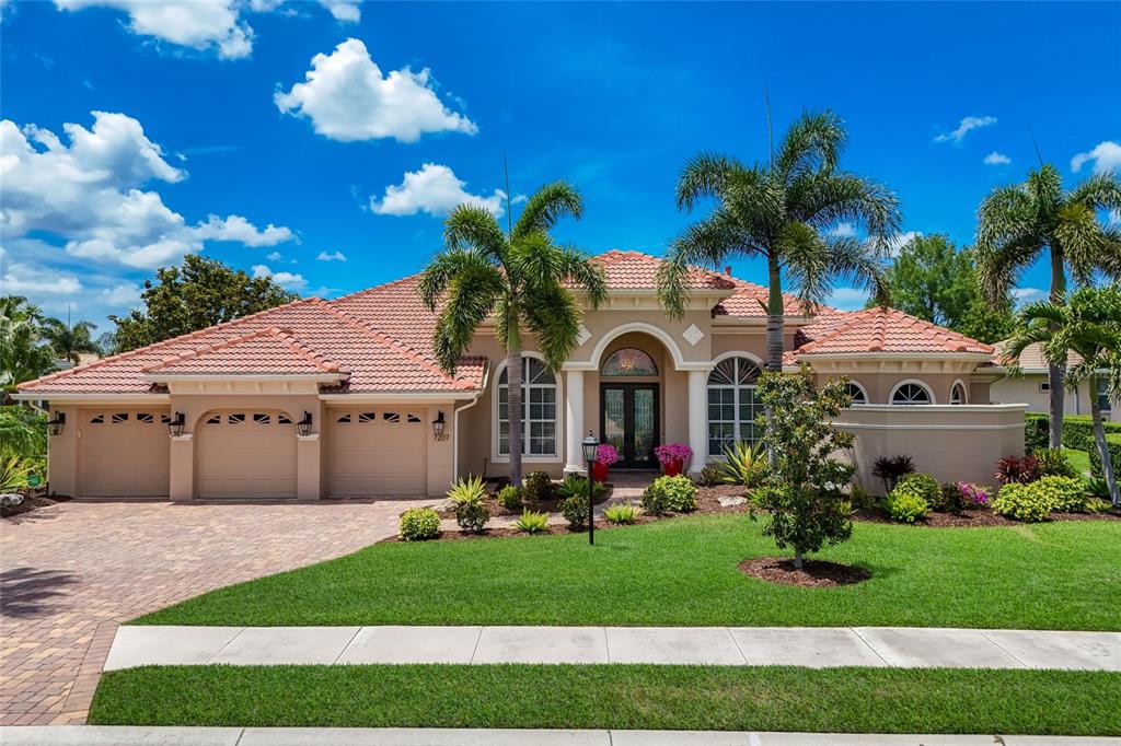 A single-story house with a tile roof, three-car garage, and palm trees in the front yard — 7207 ASHLAND GLEN, LAKEWOOD RANCH, FL