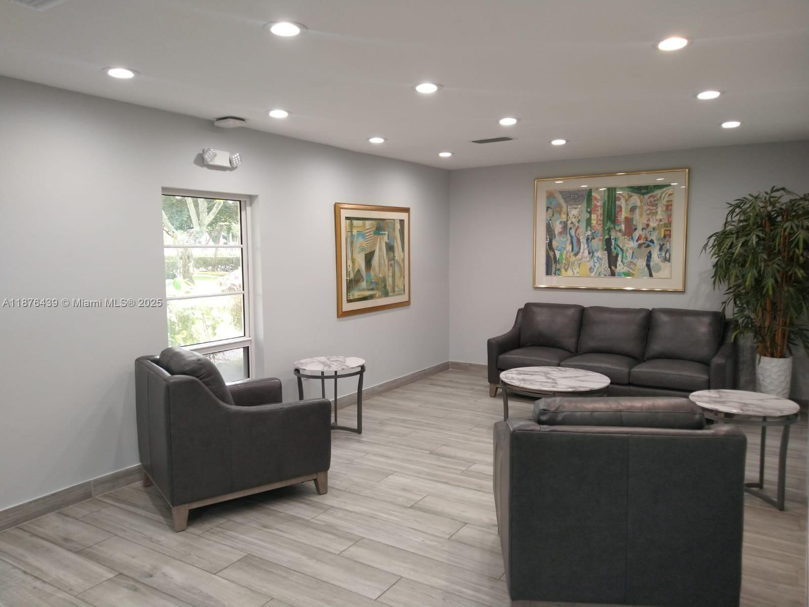 A waiting room features grey leather furniture, marble-topped tables, framed artwork, and light wood flooring — 3510 Oaks Way # 509, Pompano Beach FL 33069, POMPANO BEACH, FL
