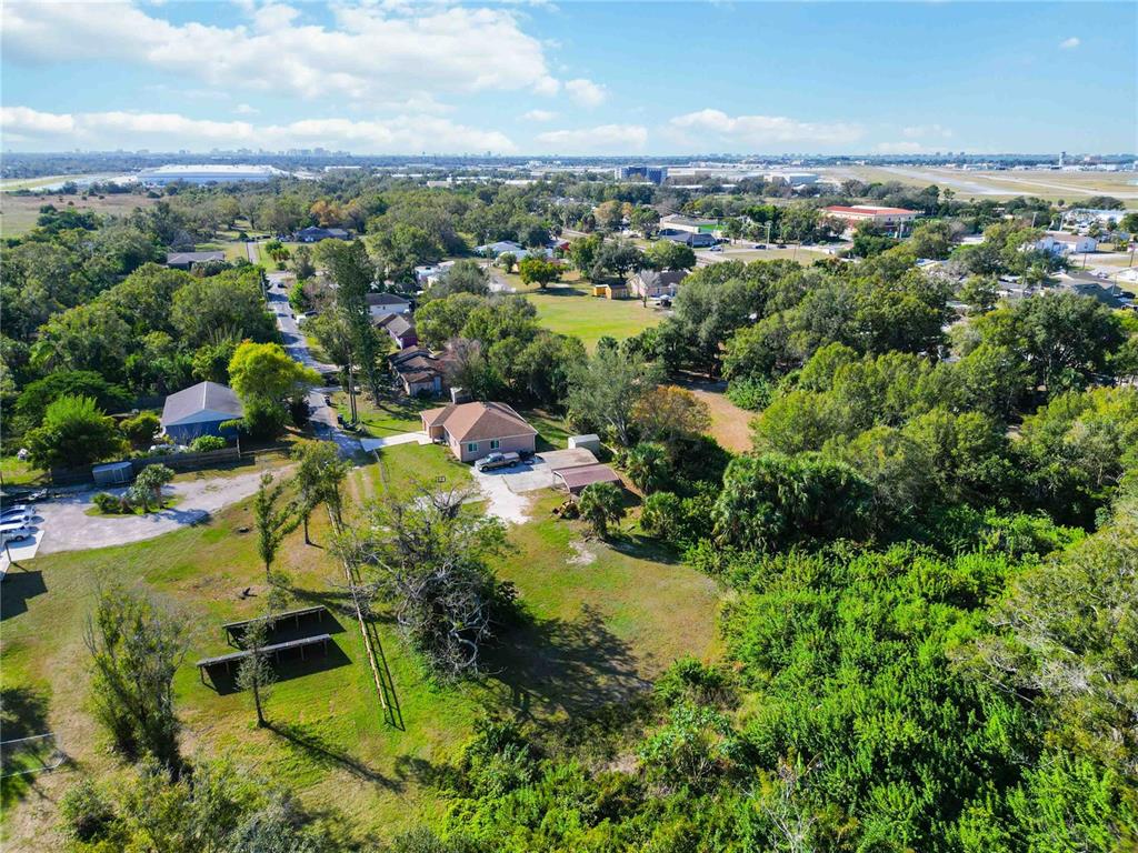 An aerial view shows a house with a driveway surrounded by trees and grassy land — 7560 19TH STREET E, SARASOTA, FL