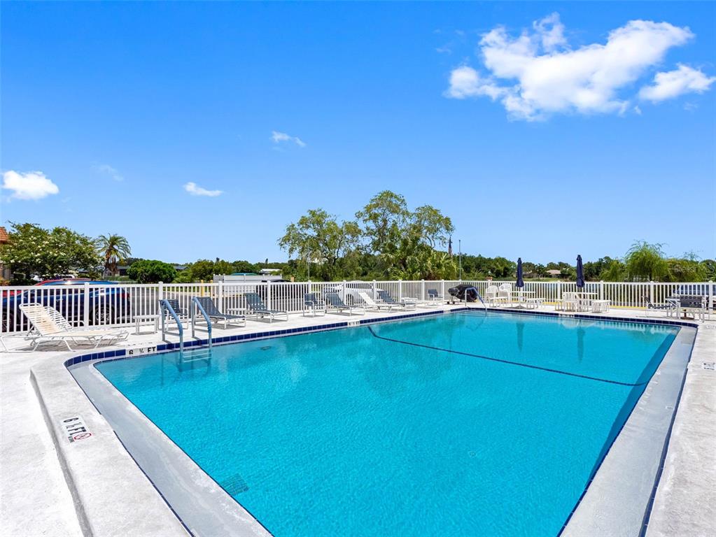 A rectangular swimming pool is surrounded by a white fence and lounge chairs — 10182 SEMINOLE ISLAND DR, LARGO, FL