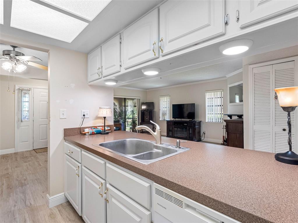 A kitchen features white cabinets, a brown countertop, a stainless steel sink, and a dishwasher — 10182 SEMINOLE ISLAND DR, LARGO, FL