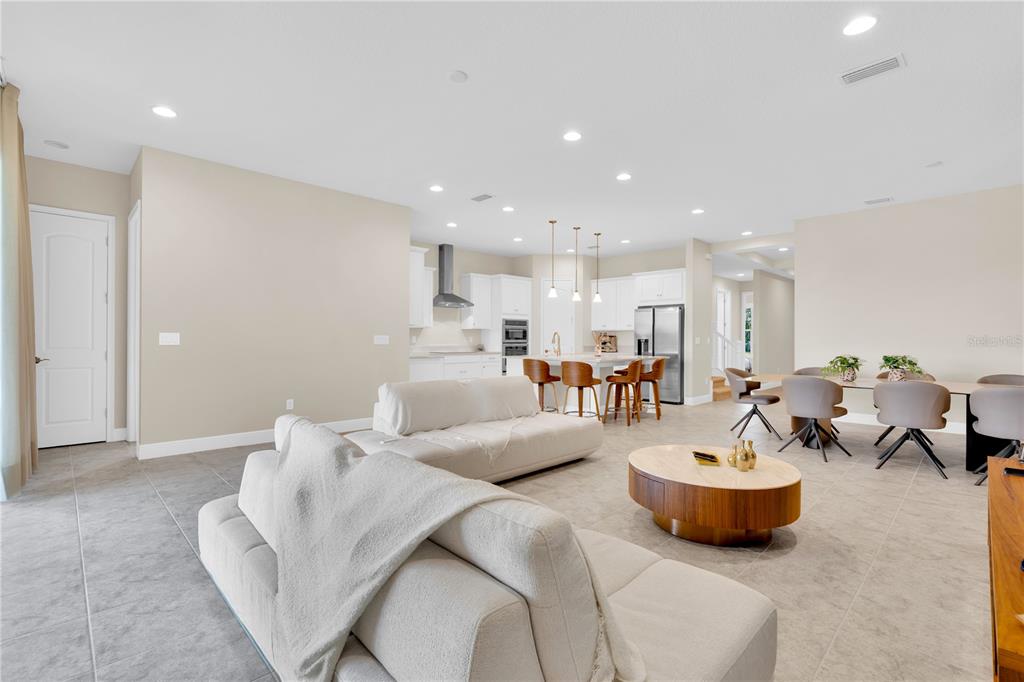 An open-concept living and dining area features tile flooring, neutral walls, and a modern kitchen — 13333 OAKENSHAW LANE, ORLANDO, FL
