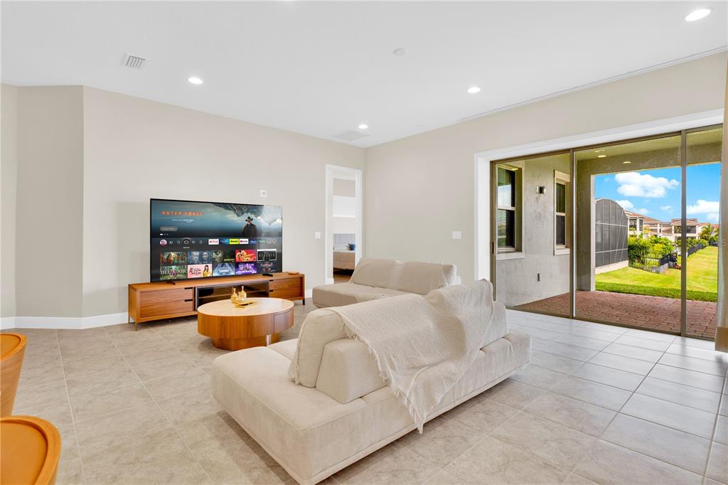 A living room features a television on a wooden console, two beige sofas, and sliding doors — 13333 OAKENSHAW LANE, ORLANDO, FL