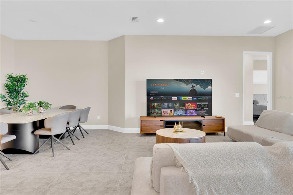 A living room and dining area with tile flooring, a television console, and neutral furniture — 13333 OAKENSHAW LANE, ORLANDO, FL
