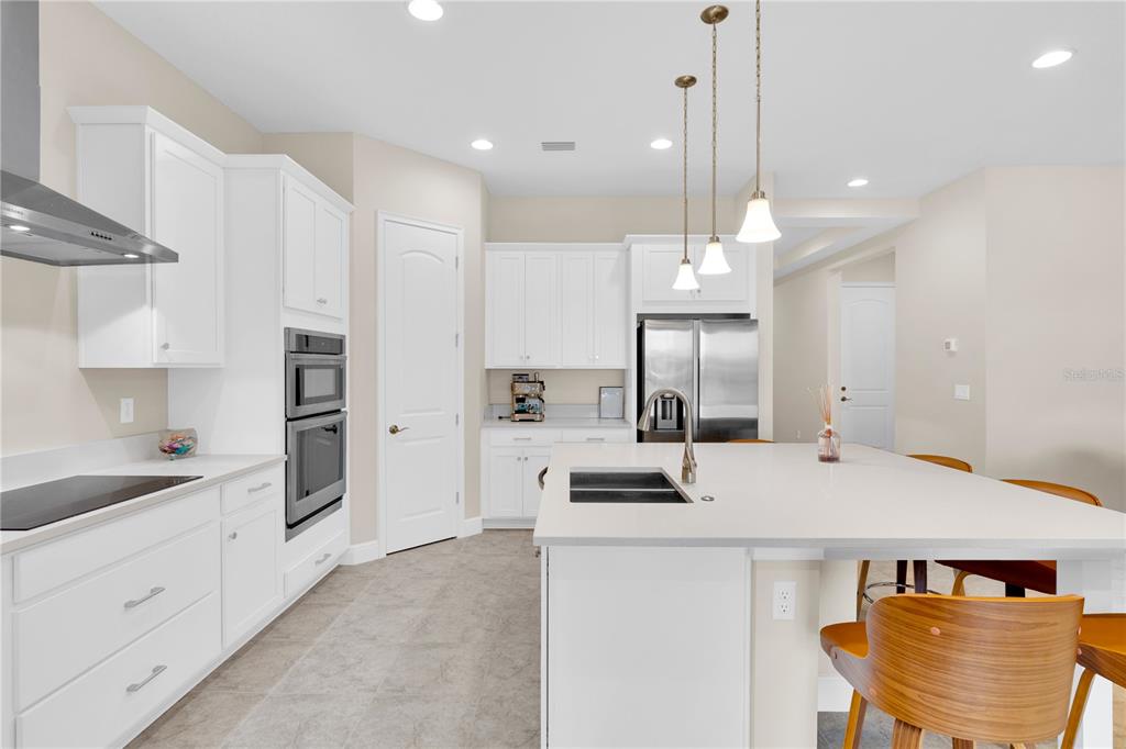 A modern kitchen features white cabinetry, stainless steel appliances, a large island, and pendant lighting — 13333 OAKENSHAW LANE, ORLANDO, FL