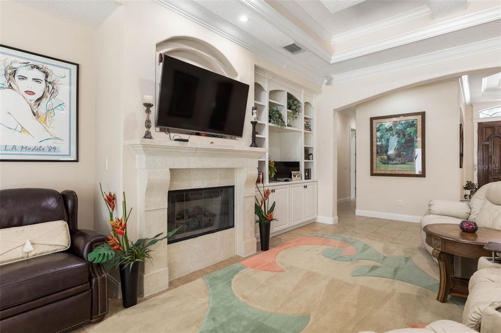 A living room features a stone fireplace with a mounted television and built-in white shelving — 34 S RIVERWALK DRIVE, PALM COAST, FL