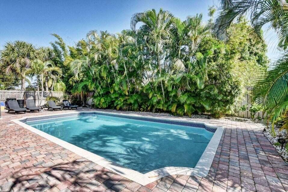 A rectangular swimming pool is surrounded by a brick paver patio and lush palm trees — 4140 Woods End Road, Boca Raton FL 33487, BOCA RATON, FL