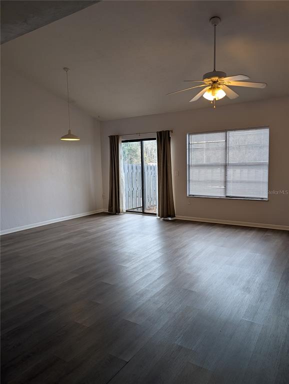 An empty living room features gray wood-look flooring, a ceiling fan, and sliding glass doors — 4342 SW 20TH LANE, GAINESVILLE, FL