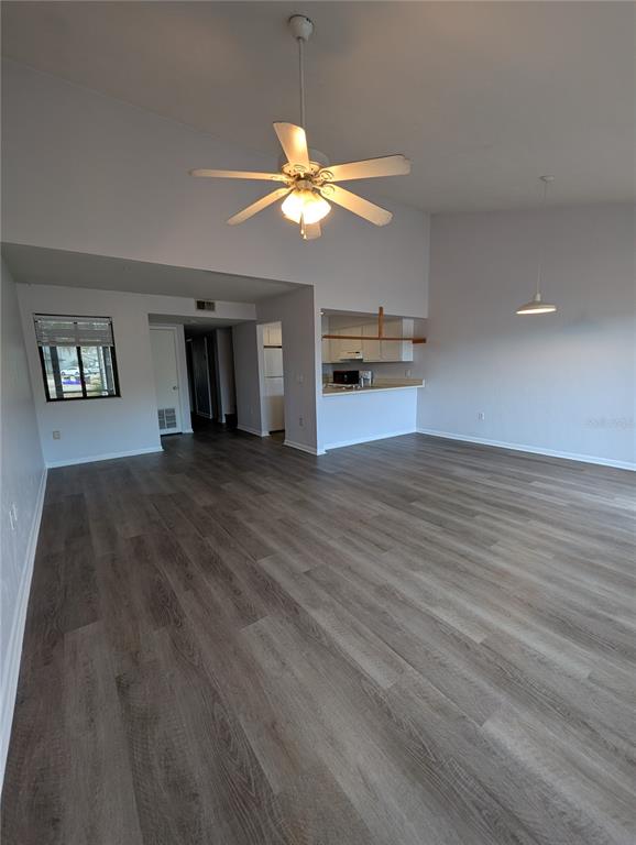 A spacious living area features vaulted ceilings, a ceiling fan, and light wood-look flooring — 4342 SW 20TH LANE, GAINESVILLE, FL