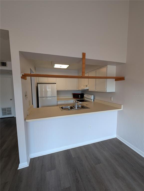 A kitchen with white cabinets, a breakfast bar, and wood-toned shelving above the counter — 4342 SW 20TH LANE, GAINESVILLE, FL