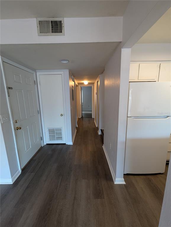 A hallway with wood-look flooring leads from an entryway past a refrigerator toward a room — 4342 SW 20TH LANE, GAINESVILLE, FL