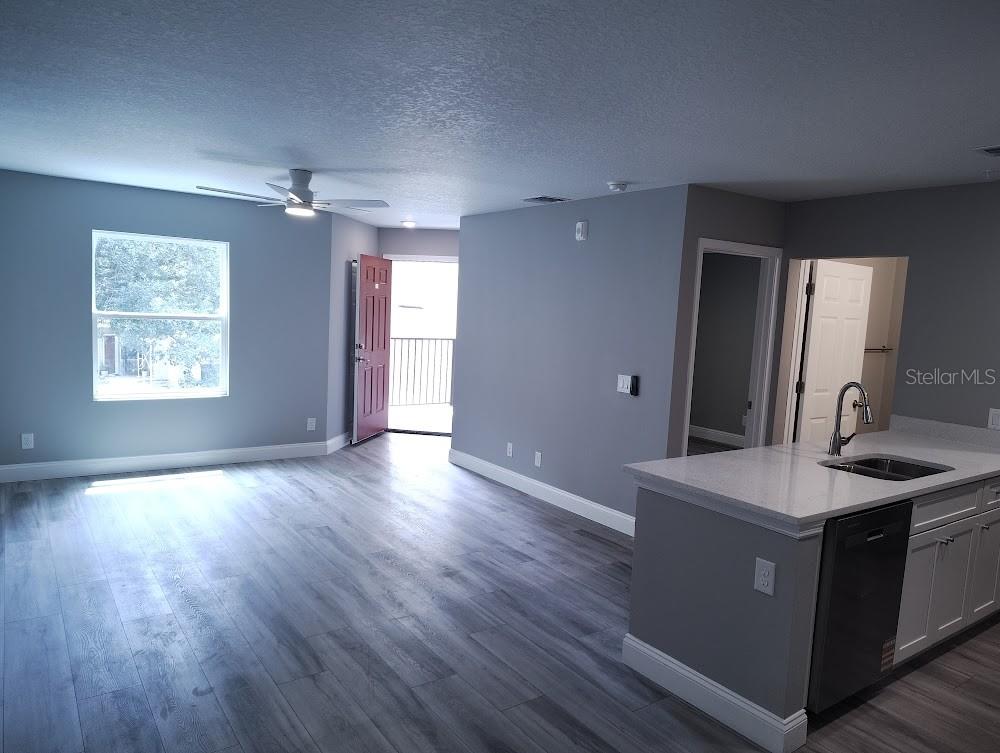 An open-concept living area features gray walls, wood-look flooring, and a kitchen with white cabinets — 3024 PARKWAY BOULEVARD UNIT 202, KISSIMMEE, FL