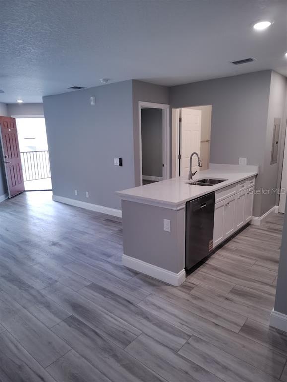 A kitchen island with a sink and dishwasher sits in an open-concept room with flooring — 3024 PARKWAY BOULEVARD UNIT 202, KISSIMMEE, FL