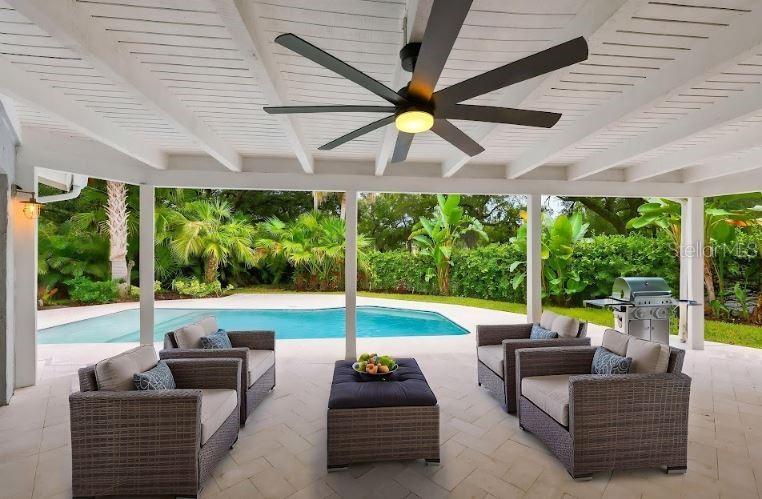 A covered patio features wicker furniture, a ceiling fan, and a view of a swimming pool — 13904 HAYWARD PLACE, TAMPA, FL