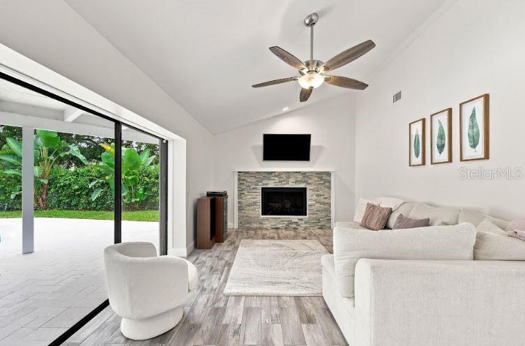 A living room features a stone fireplace, a ceiling fan, and a large sliding glass door — 13904 HAYWARD PLACE, TAMPA, FL