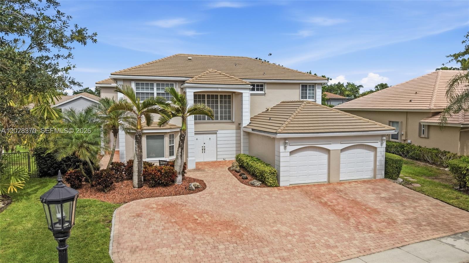 A two-story house with a tiled roof, a brick driveway, and a two-car garage — 2608 Oakbrook Ct, Weston FL 33332, WESTON, FL
