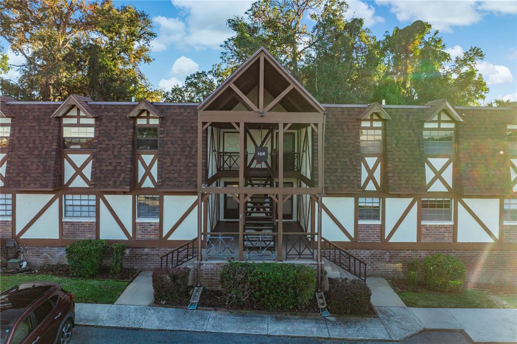 A two-story Tudor-style apartment building with a central wooden staircase and brown shingled roof — 500 NEWELL HILL ROAD UNIT 106D, LEESBURG, FL