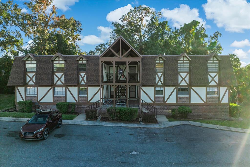 A two-story apartment building with Tudor-style architecture and a central open-air staircase — 500 NEWELL HILL ROAD UNIT 106D, LEESBURG, FL