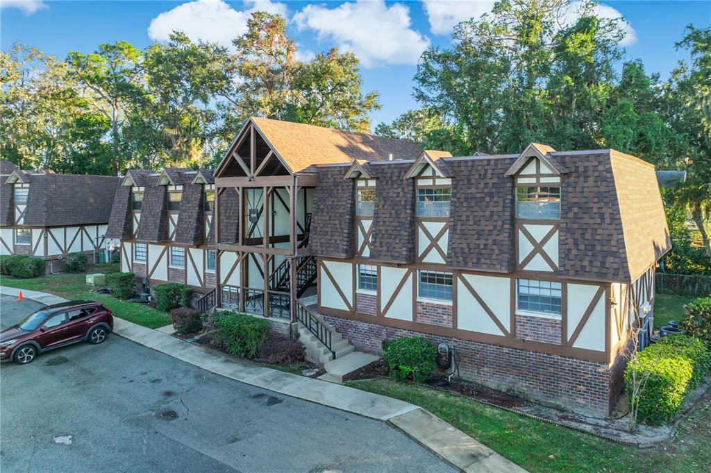A two-story Tudor-style apartment building with a brown shingled roof and brick lower exterior — 500 NEWELL HILL ROAD UNIT 106D, LEESBURG, FL