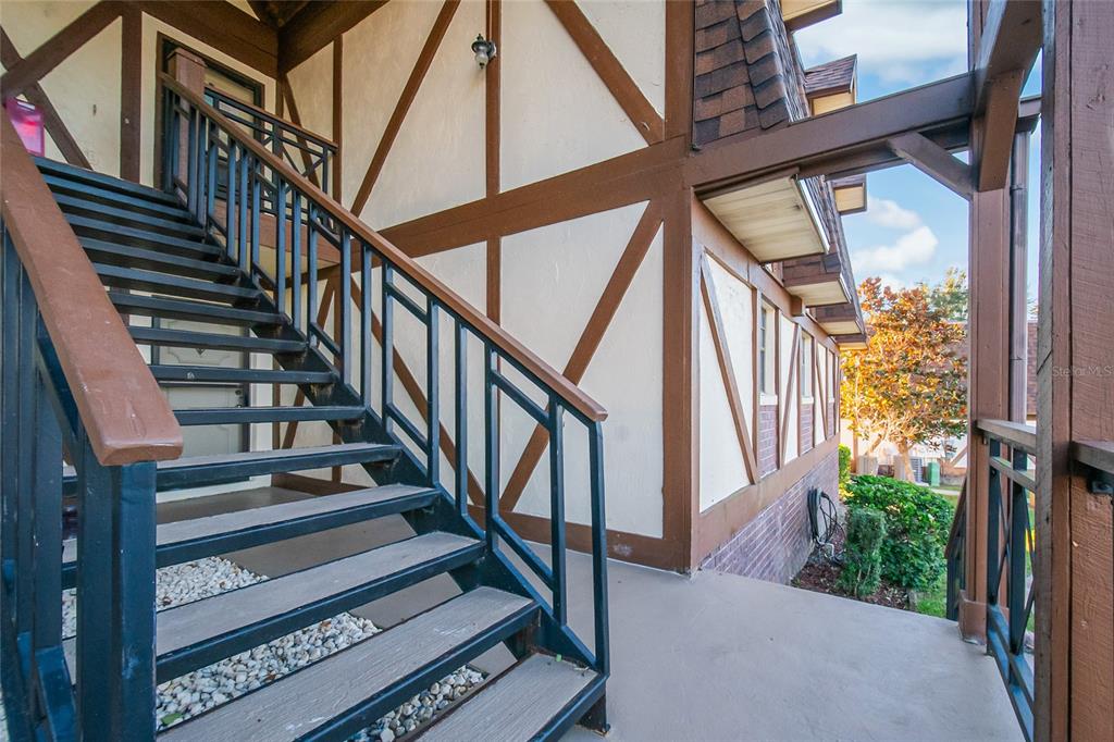 An exterior view of a Tudor-style building featuring a metal staircase leading to an entrance — 500 NEWELL HILL ROAD UNIT 106D, LEESBURG, FL