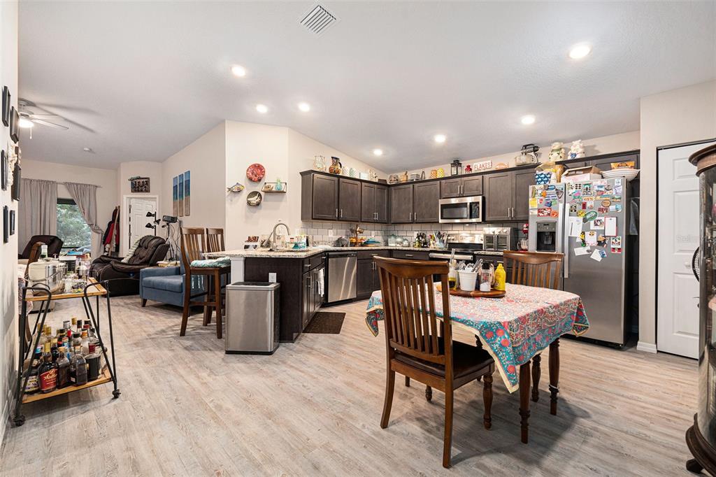A kitchen with dark cabinets, stainless steel appliances, and a dining table in the foreground — 10425 S DREW BRYANT CIRCLE, FLORAL CITY, FL