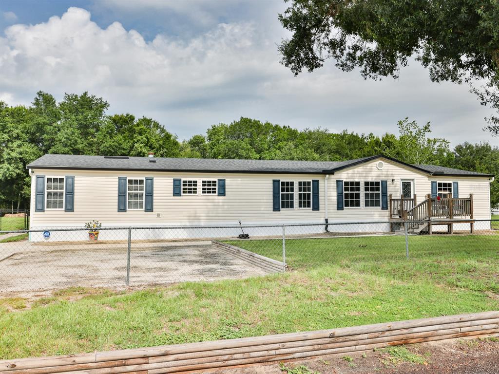 A single-story manufactured home with light siding, blue shutters, and a wooden deck — 1120 SADDLEWOOD BOULEVARD, LAKELAND, FL