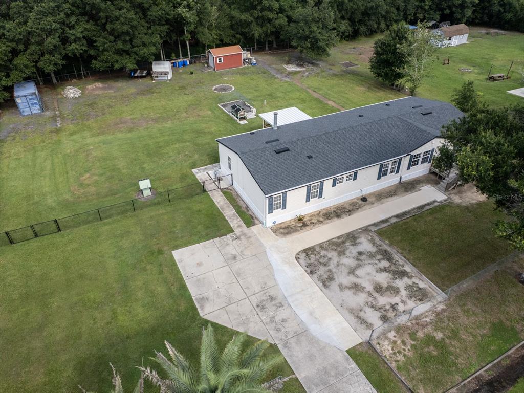 An aerial view shows a manufactured home with a concrete driveway and a large yard — 1120 SADDLEWOOD BOULEVARD, LAKELAND, FL