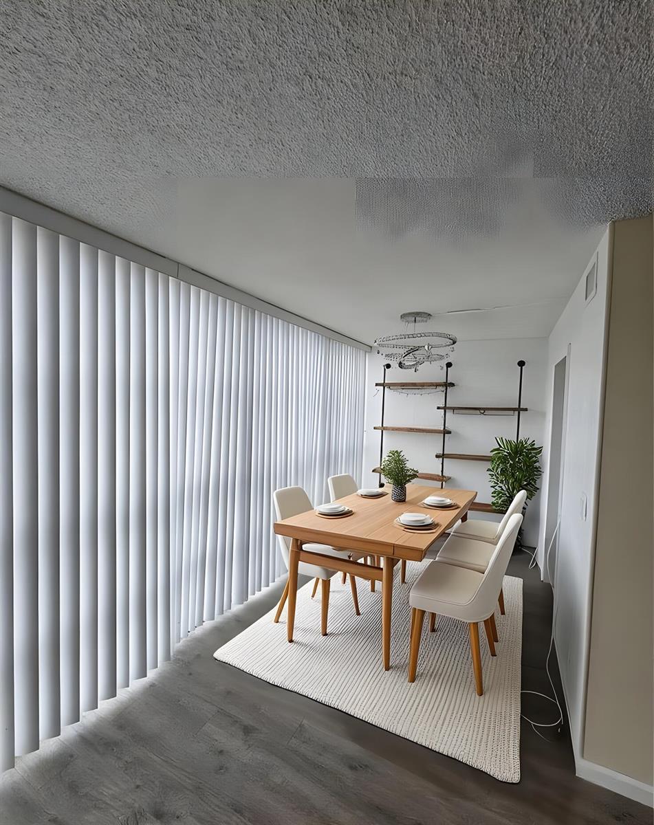 A dining room features a wooden table, white chairs, a rug, and vertical window blinds — 801 Three Islands Boulevard # 409, Hallandale Beach FL 33009, HALLANDALE BEACH, FL