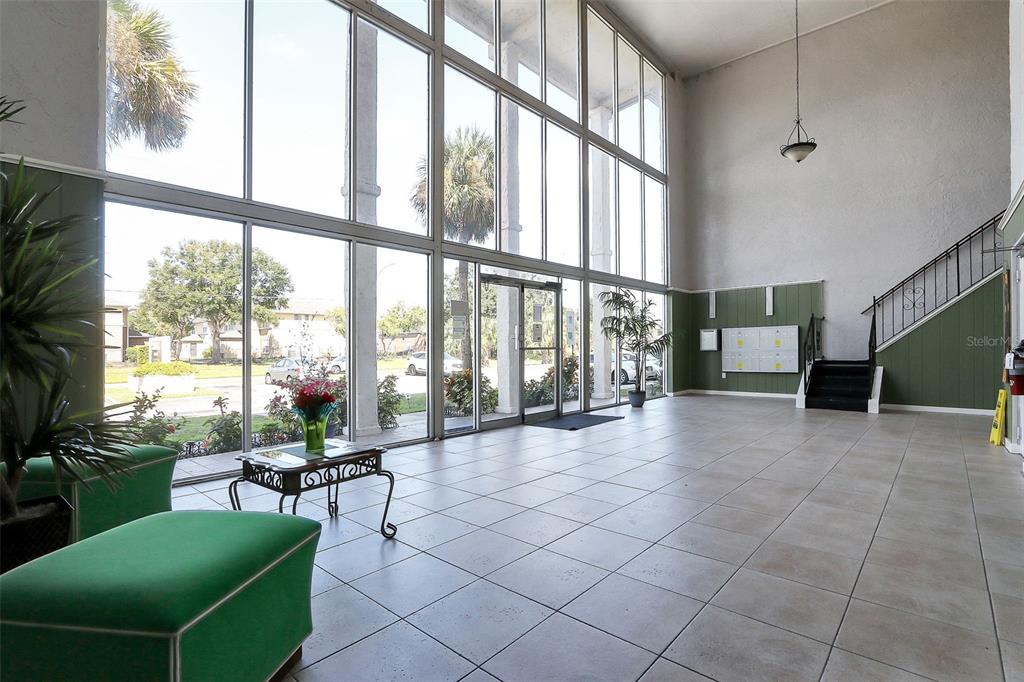 A bright lobby features floor-to-ceiling windows, tile flooring, green accent walls, and a staircase — 1902 HONOUR ROAD UNIT 11, ORLANDO, FL